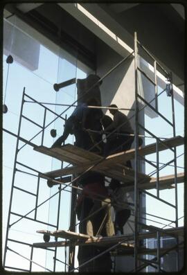 Workers securing a totem pole in the Museum of Anthropology
