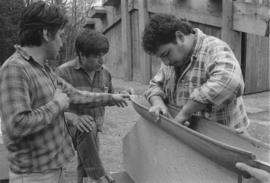 [Chip, Norman and Ron inspect and discuss model canoe]