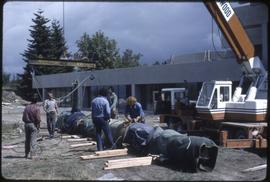 Workers preparing a totem pole to be lifted
