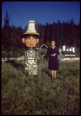 Woman next to short totem pole
