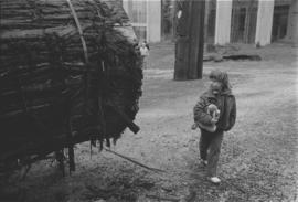 [Unidentified child walking near base of canoe log]