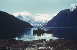 Fishing boat on water with snow covered mountains in background