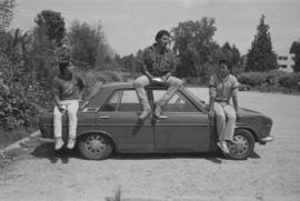 [Isaac, Ron, and Chip sit on top of car]