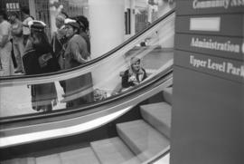 [Tait family members and unidentified person near escalator]