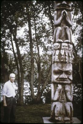 Man standing next to totem pole