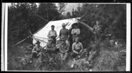Group portrait of nine men in front of tent