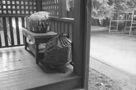 [Full garbage bag next to table on porch]