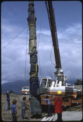 A totem pole being lifted by a crane