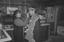 [Reva Robinson assists Norman Tait in carving hut]