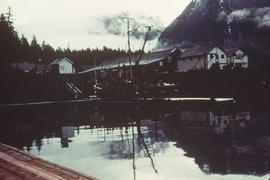 Fishing boat docked by village, with mountains in background