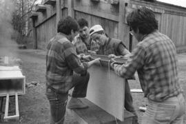 [Chip, Norman, Isaac and Ron inspect model canoe post-steaming]