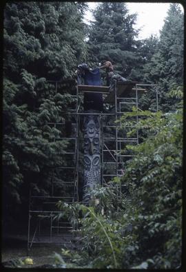 Workers prepare to move a totem pole