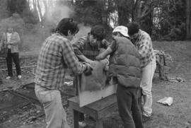 Chip, Norman, Isaac [and] Ron pressing edges [of model canoe] together