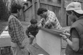 [Chip, Norman, Ron and Isaac inspect model canoe]