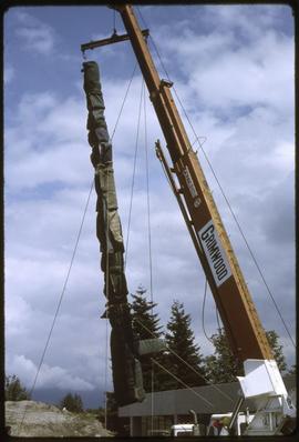A totem pole being lifted by a crane