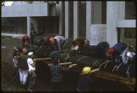 Workers unloading totem poles from a trailer