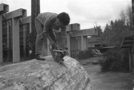 [Norman uses chainsaw to cut into top of log]